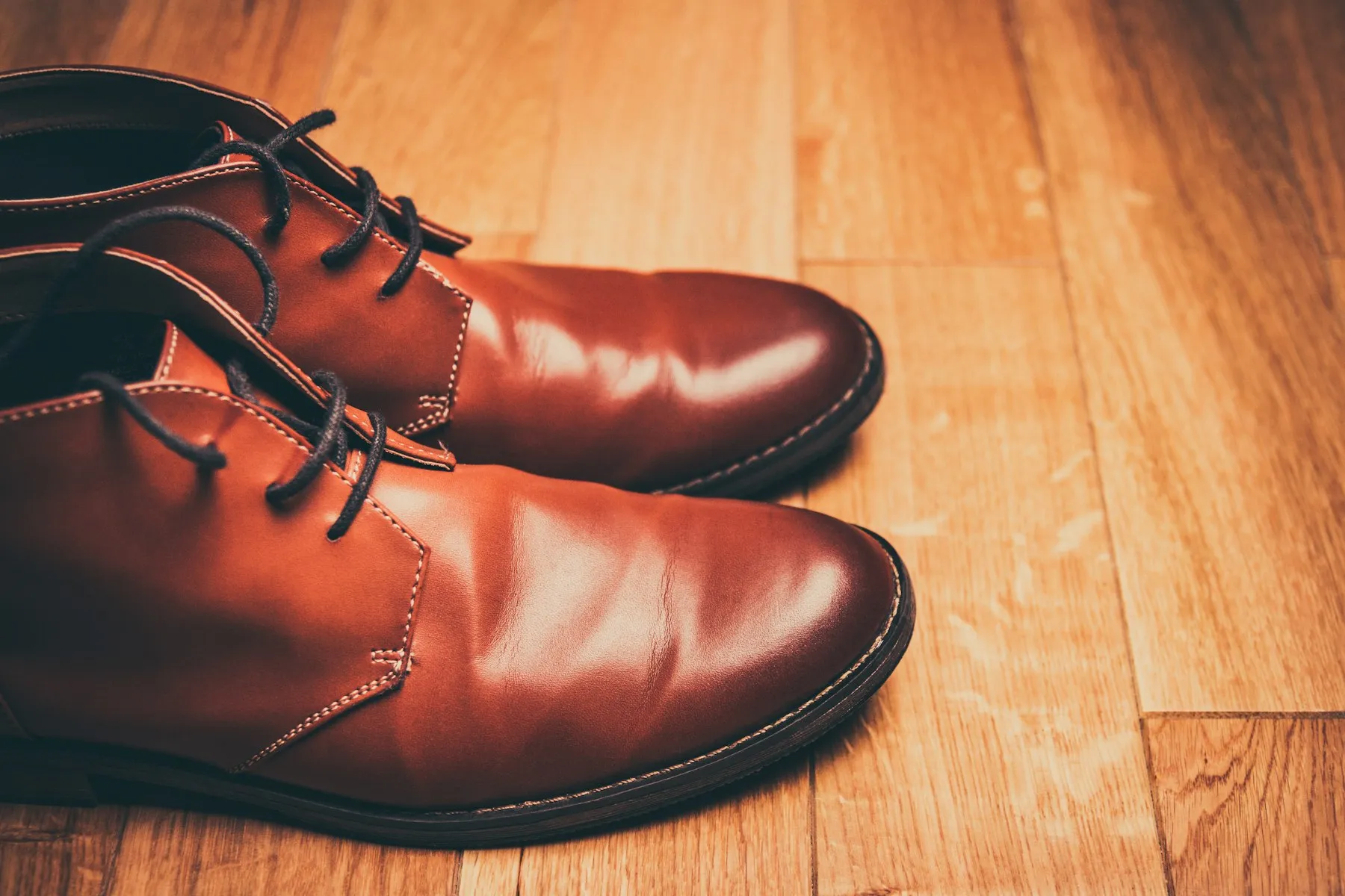 Braune Lederschuhe mit Schnürung auf warmem Holzboden